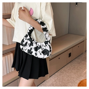 Detail of ruched cow print underarm bag shown with casual lifestyle outfit