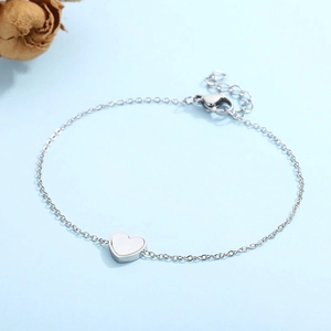 Detailed close-up of a silver heart-shaped bracelet with shell inlay and lobster clasp