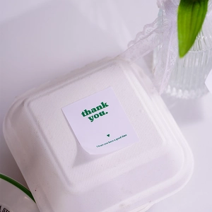 Macro detail of rectangle 'thank you' sticker on a white eco-friendly pulp box