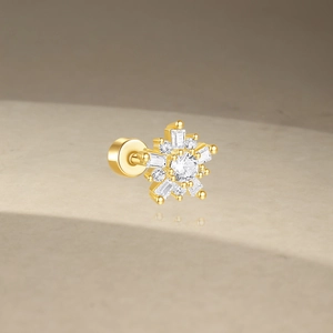 Close-up of golden snowflake stud earring with clear zircon and screw back design