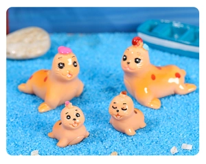 Close-up of four miniature resin seals with red dots on decorative blue sand scenery