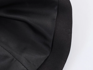 Detailed macro view of black textured fabric and reinforced stitching on the pleated blazer