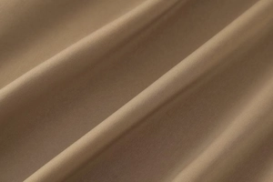 Vue macro détaillée du tissu satiné marron clair montrant la texture lisse et le drapé