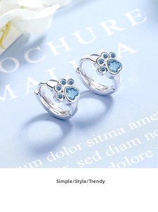 Detail view of heart-shaped cat paw earrings with blue zircon in silver setting