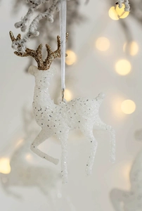 Macro shot of white glitter reindeer ornament with gold antlers and festive bokeh lights