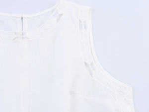 Détail du haut blanc sans manches avec dentelle ajourée géométrique et col rond élégant