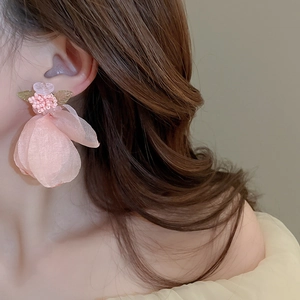 Detail showing the pink fabric flower earring with delicate bead center on model