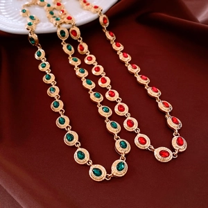 Close-up of vintage gold oval necklace with red and green crystals on silk fabric