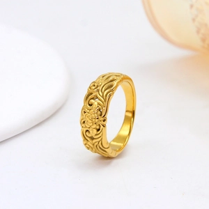 Detail of vintage gold-finished ring with intricate floral and wave texture engravings