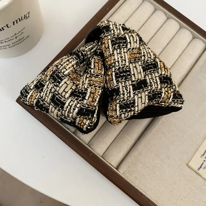 Détail de la pince à cheveux en tweed avec texture tissée noire, blanche et dorée