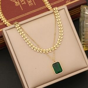 Double-layered gold necklace featuring wheat chain and emerald green square pendant