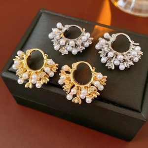 Detailed view of U-shaped pearl earrings with cubic zirconia on black leather box