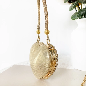Detail of a gold heart-shaped evening bag featuring rhinestones and a metal chain strap