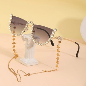 Detail of cat-eye sunglasses with rhinestone edges and a gold star element chain