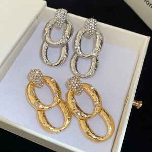 Macro shot of oval earrings with hammered metal texture and sparkling zircon inlay details