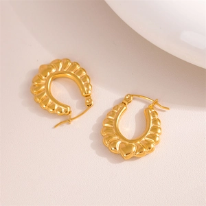 Polished gold heart hoop earrings with textured pattern shown in a professional studio shot