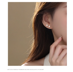 Close-up detail of silver S925 cross stud earrings worn by model with minimalist style