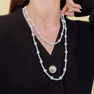 Close-up of double-layer white faux pearl necklace on a black knit cardigan sweater