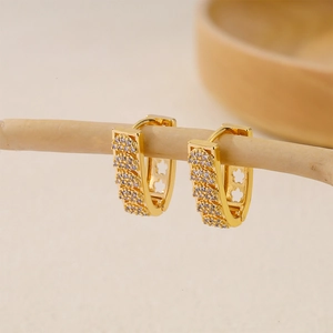 Detailed close-up of gold V-shaped huggie earrings with pave zircon and hollow flower pattern
