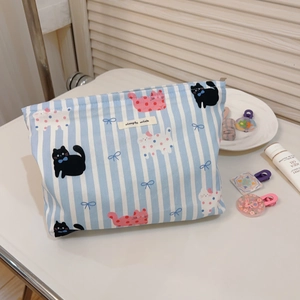 Détail d'une trousse de maquillage en toile à rayures bleues avec imprimé chat et fermeture éclair