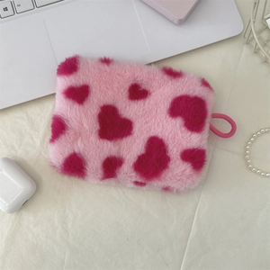Pink plush heart coin purse with lanyard ring on beige fabric with tech accessories