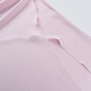 Detailed macro view of pink satin fabric with delicate jacquard patterns and stitch edges