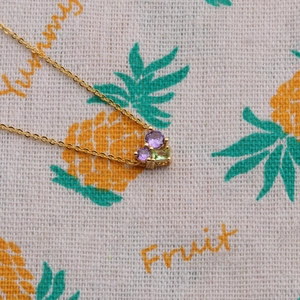 Collier élégant doré avec pendentif cœur et pierres de zircon violettes et vertes sur tissu