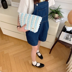 Close-up of soft blue and white striped plush vanity bag with zipper and logo label