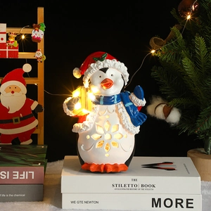 Detail of penguin Christmas resin night light with hollow snowflake design and glowing gift box