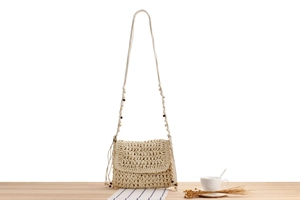 Detail shot of handwoven beige straw shoulder bag with decorative wooden beads and wavy texture