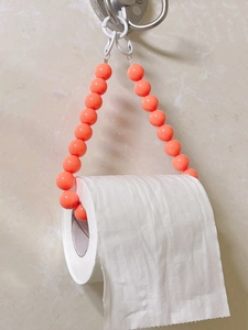 Detail of pink beaded toilet paper holder hanging on a bathroom wall hook