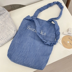 Detail of blue plaid canvas tote with Sozaka embroidery and ruffled shoulder strap