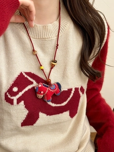 Detail of red fabric pony pendant with blue flower embroidery on wooden beaded necklace
