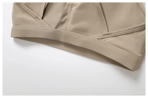 Macro detail of the cross-layered hem and fine stitching on a khaki sports bra