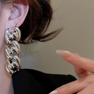 Close-up of a chunky silver chain earring on a model for a bold luxury jewelry look