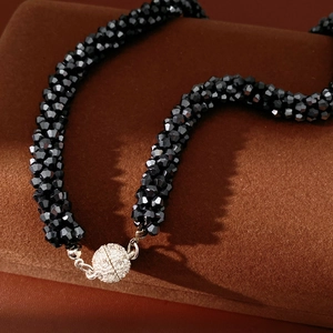 Detailed close-up of a multi-strand black beaded necklace with a sparkling diamond magnetic clasp