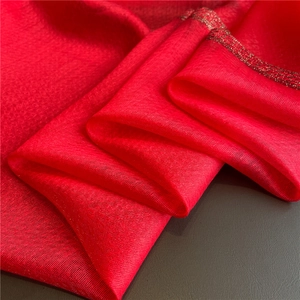 Detalle de bufanda de seda roja con ribete de lentejuelas doradas y textura suave