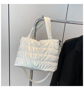 Detailed view of white quilted puffer tote bag displayed on a sleek metal rack