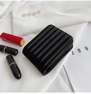 Mini black pleated makeup pouch for lipstick with textured fabric on a white blazer