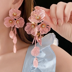 Détail de boucles d'oreilles pendantes fleurs roses en maille avec strass