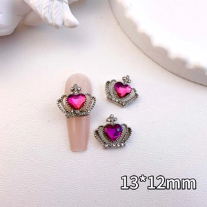 Close-up of 13x12mm silver crown nail charms with pink heart rhinestones for manicure
