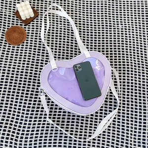 Detail of purple heart-shaped transparent PVC shoulder bag with white strap on checkered cloth