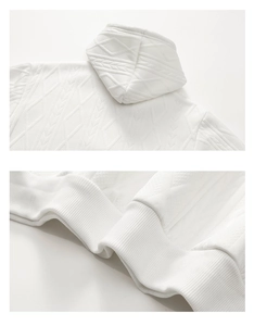 Detail eines weißen Kapuzenpullovers mit geometrischer Textur und geripptem Saum
