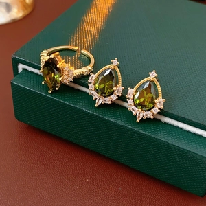 Dettaglio di anello e orecchini placcati oro con zirconi a goccia verde oliva