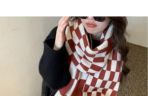 Close-up of red and white checkerboard knit scarf texture on model with soft thick fabric
