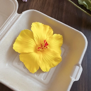 Detail of yellow acrylic flower hair clip with red stamen on a wooden background