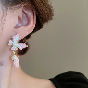 Détail de la boucle d'oreille papillon avec perle et pendentif muguet sur mannequin