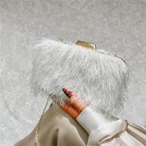 Detail of white faux fur clutch featuring a golden metal clasp and elegant chain strap