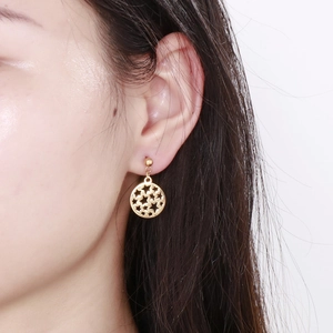 Close-up of a model wearing golden circular hollow star earrings with stud attachment