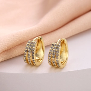 Macro shot of gold-plated huggie earrings featuring triple rows of cubic zirconia pavé